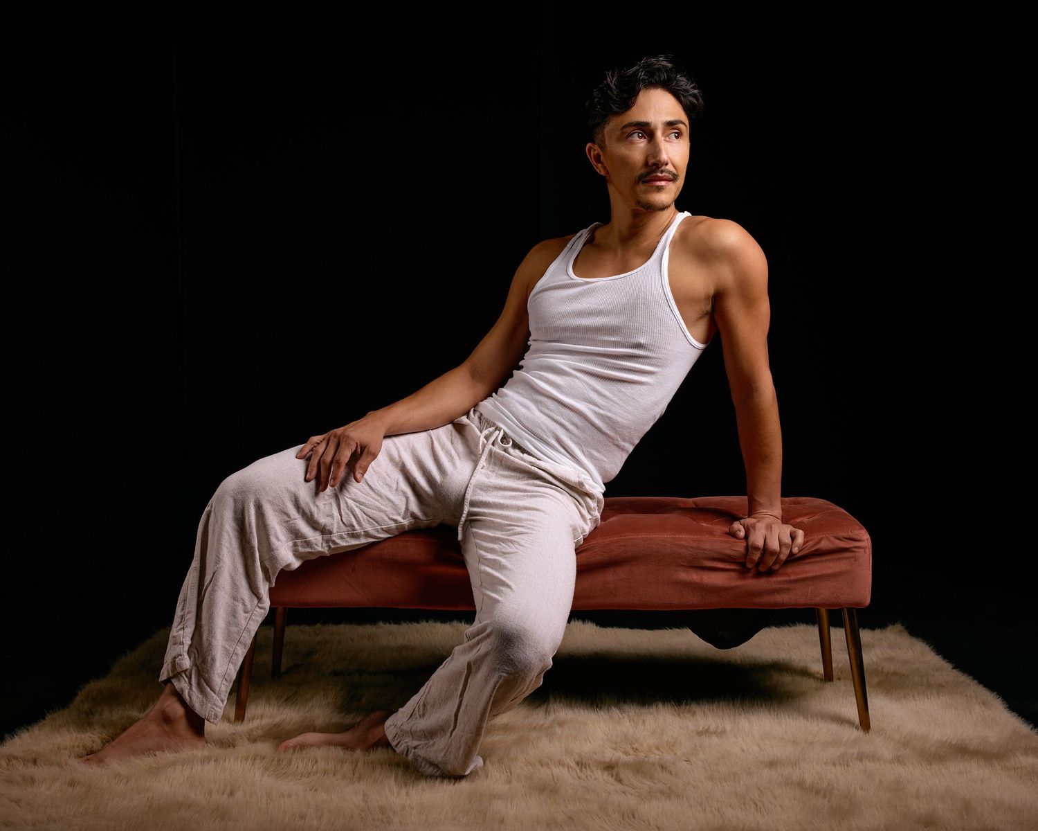 Long Beach male editorial photo series showing athletic poses on brown bench against dark background.