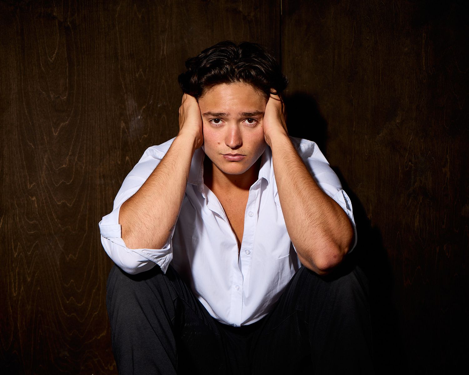 Expressive portrait series showing emotional poses in white shirt against dark backdrop.