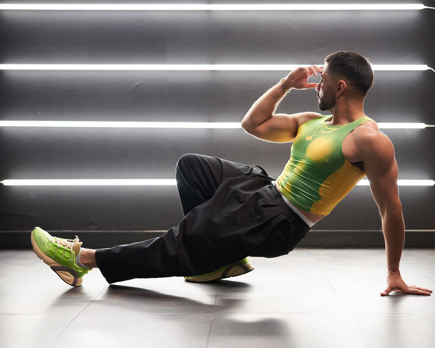 Athletic figure performing dynamic breakdance moves on white floor with fluorescent lighting.