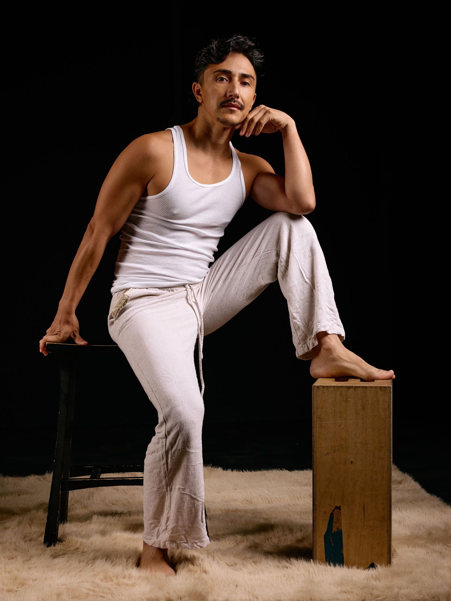 Figure in white tank top performing dynamic poses with wooden box prop.