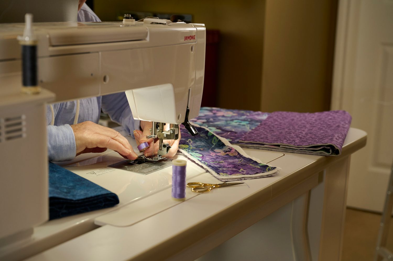 Sewing workstation set up in a bright craft room with purple fabric visible.