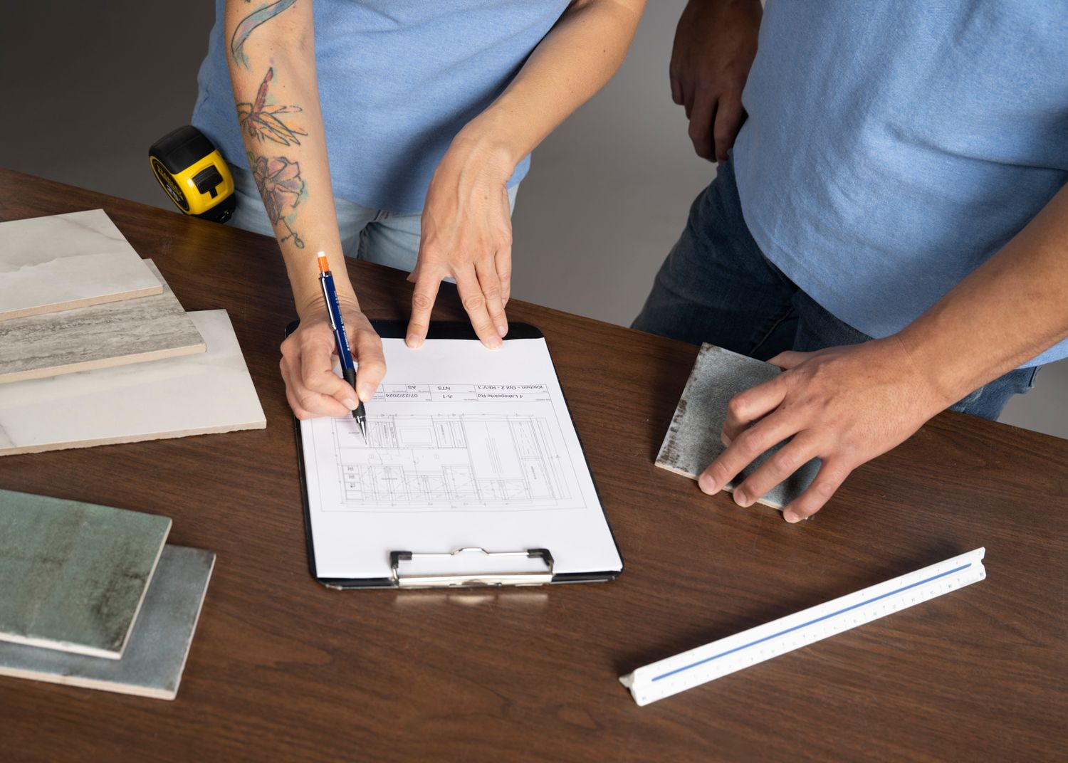 Person filling out paperwork on a wooden desk with writing materials and supplies.