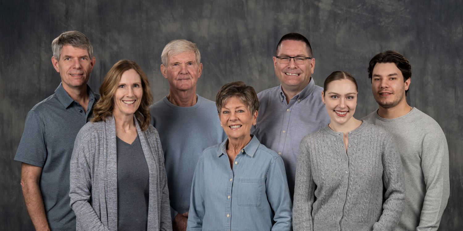 A group of people wearing casual gray and blue attire pose together for a formal portrait photograph.