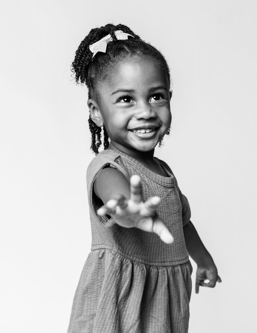 A series of playful black and white portraits showing a child in a gray dress.
