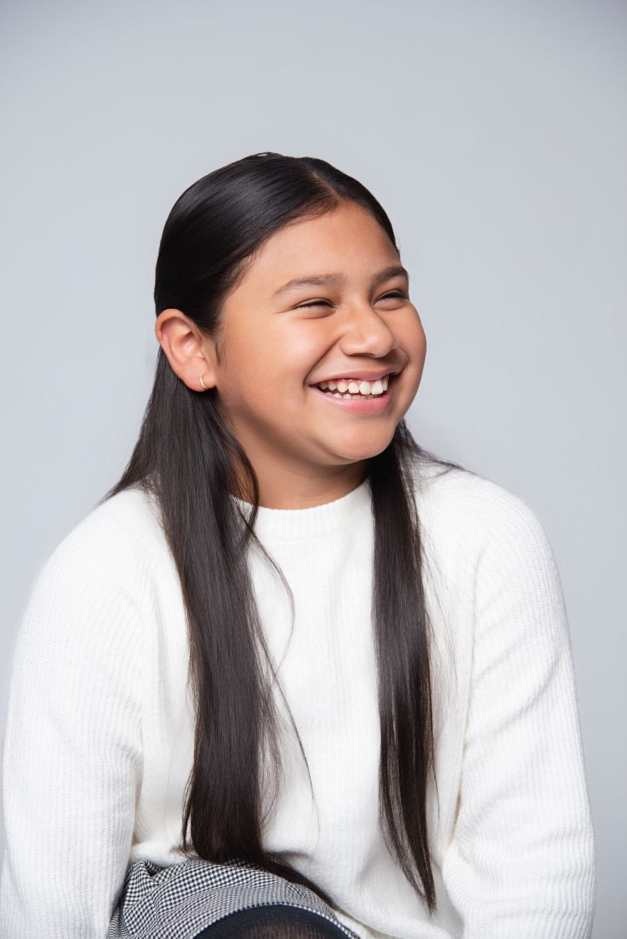 Four sequential photos showing someone in a white sweater expressing joyful laughter against a gray background.