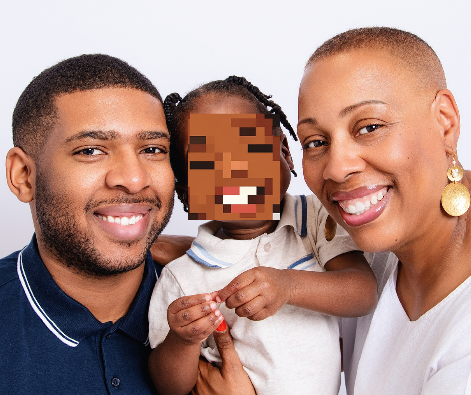 A smiling family of three, with two adults and a young toddler, posing together against a light background.