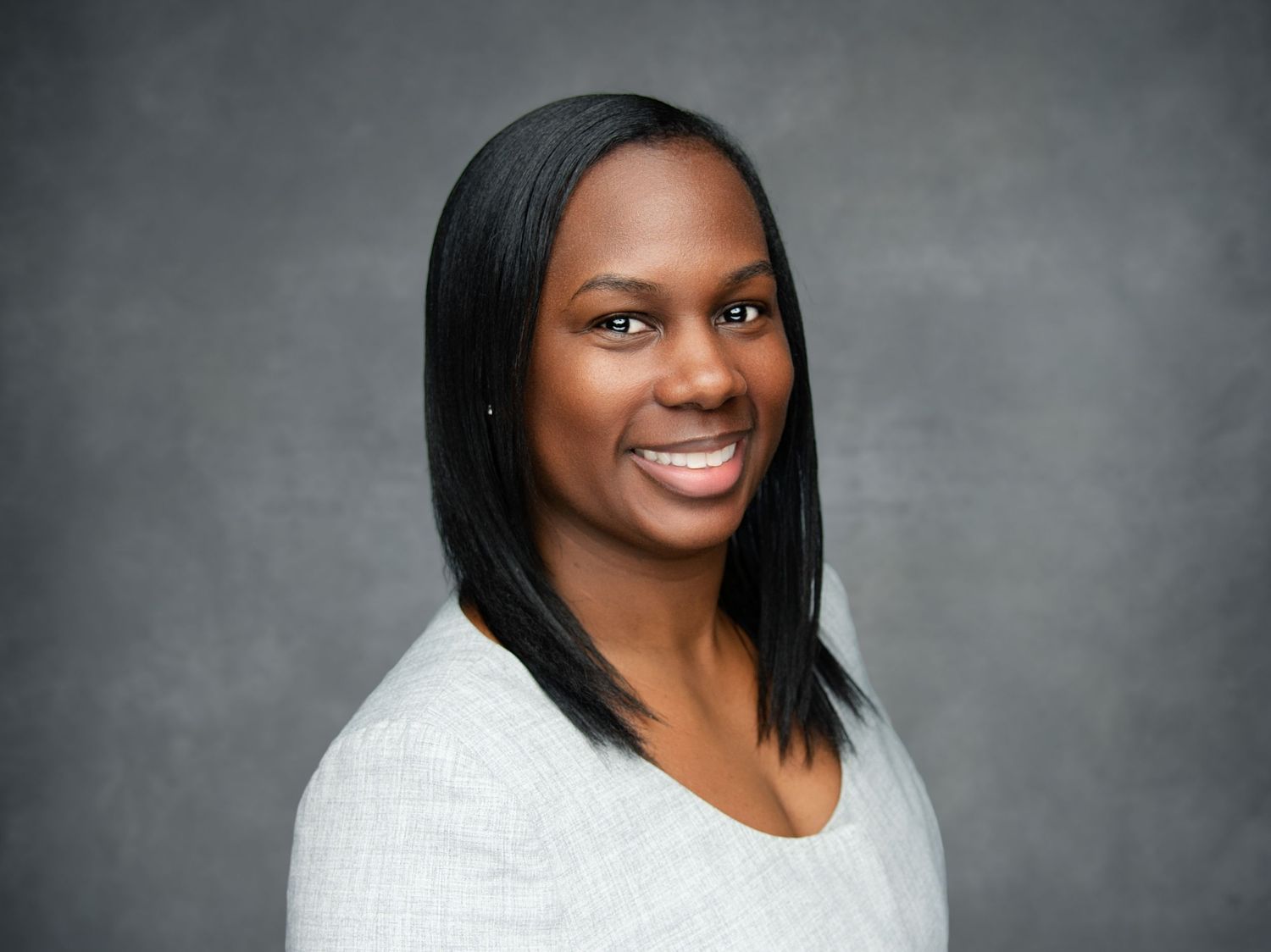 Professional headshot portraits against a gray background showing warm, engaging smiles.