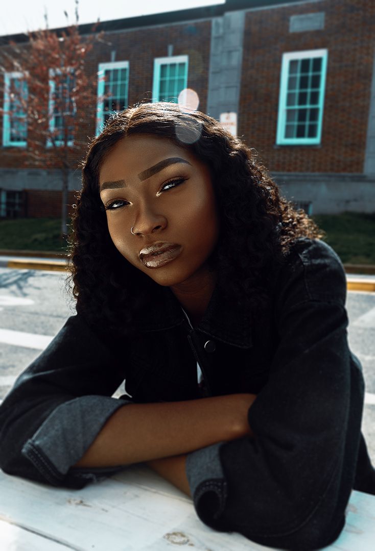 A series of artistic portrait shots showing someone in a black outfit against a brick building background.