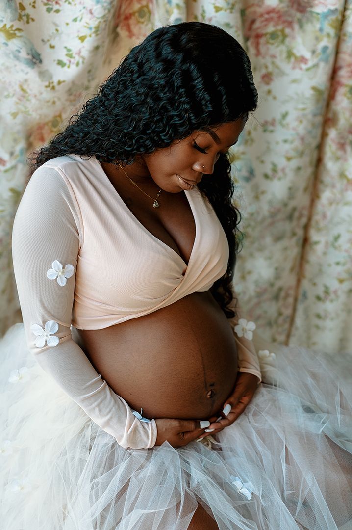 Maternity photoshoot featuring someone in a white tulle skirt and delicate butterflies.