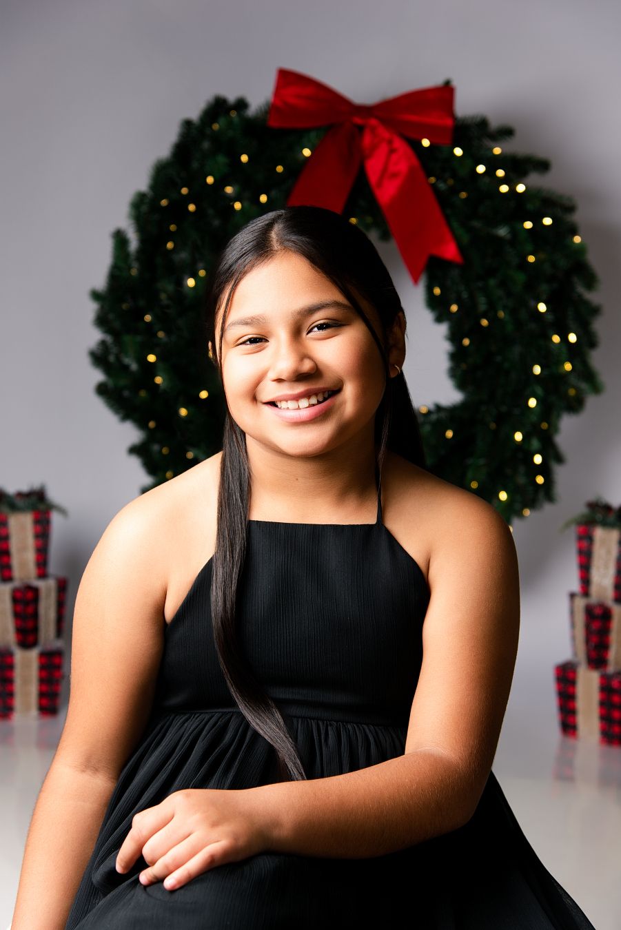Holiday portraits with festive Christmas wreath and wrapped presents in the background against a gray backdrop.
