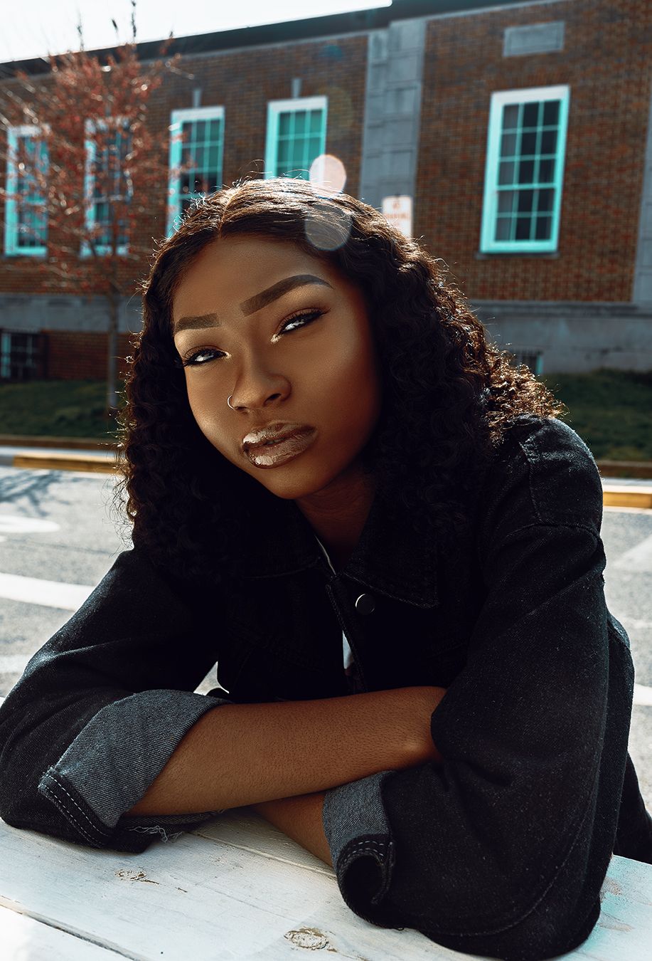 A series of outdoor portrait photographs showing someone in a black top posing against a brick building background.