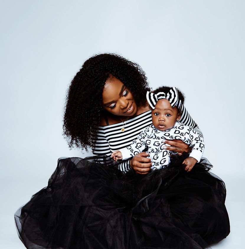 Mother and baby in matching striped outfits with black tulle skirt against white background.