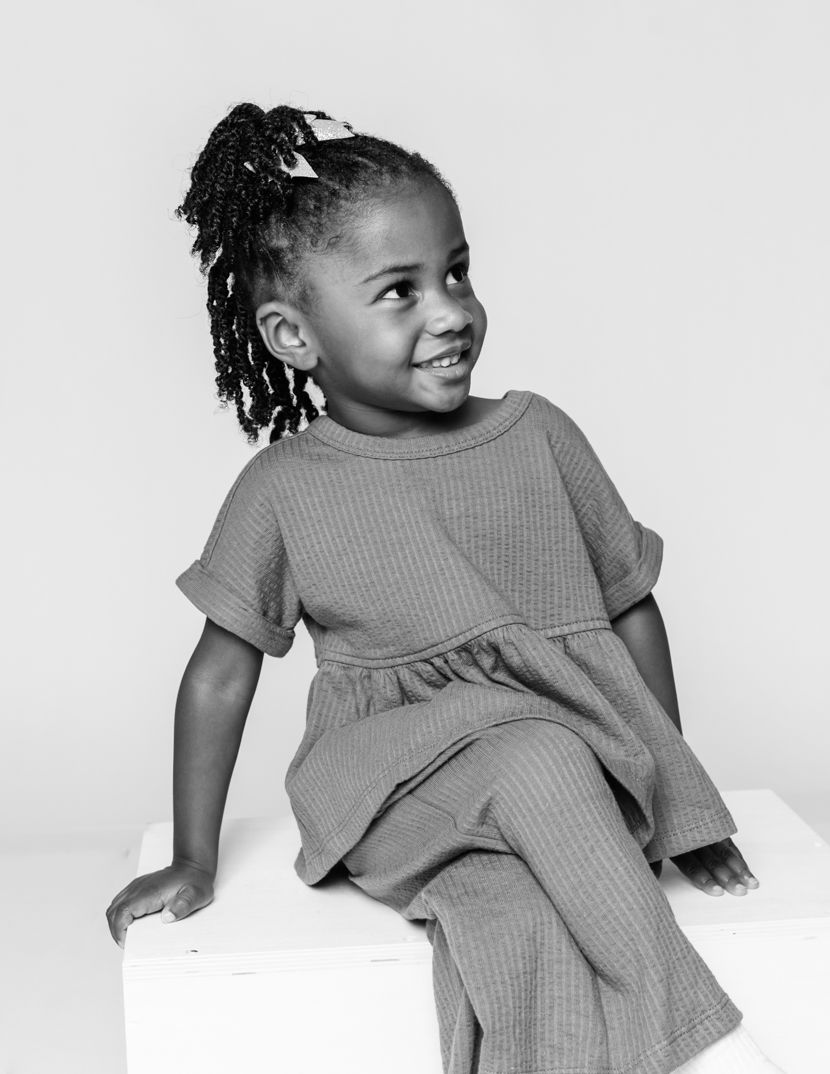 Multiple poses of a young child wearing a gray ribbed dress against a white background.