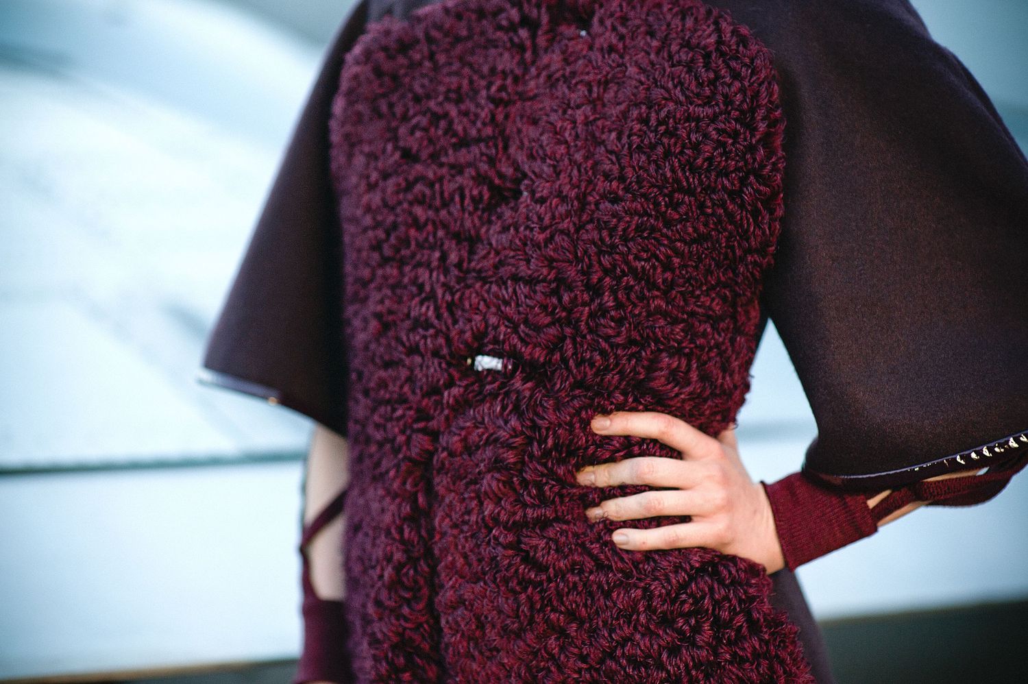 Fashion detail shots of a deep burgundy textured garment against a blue background.