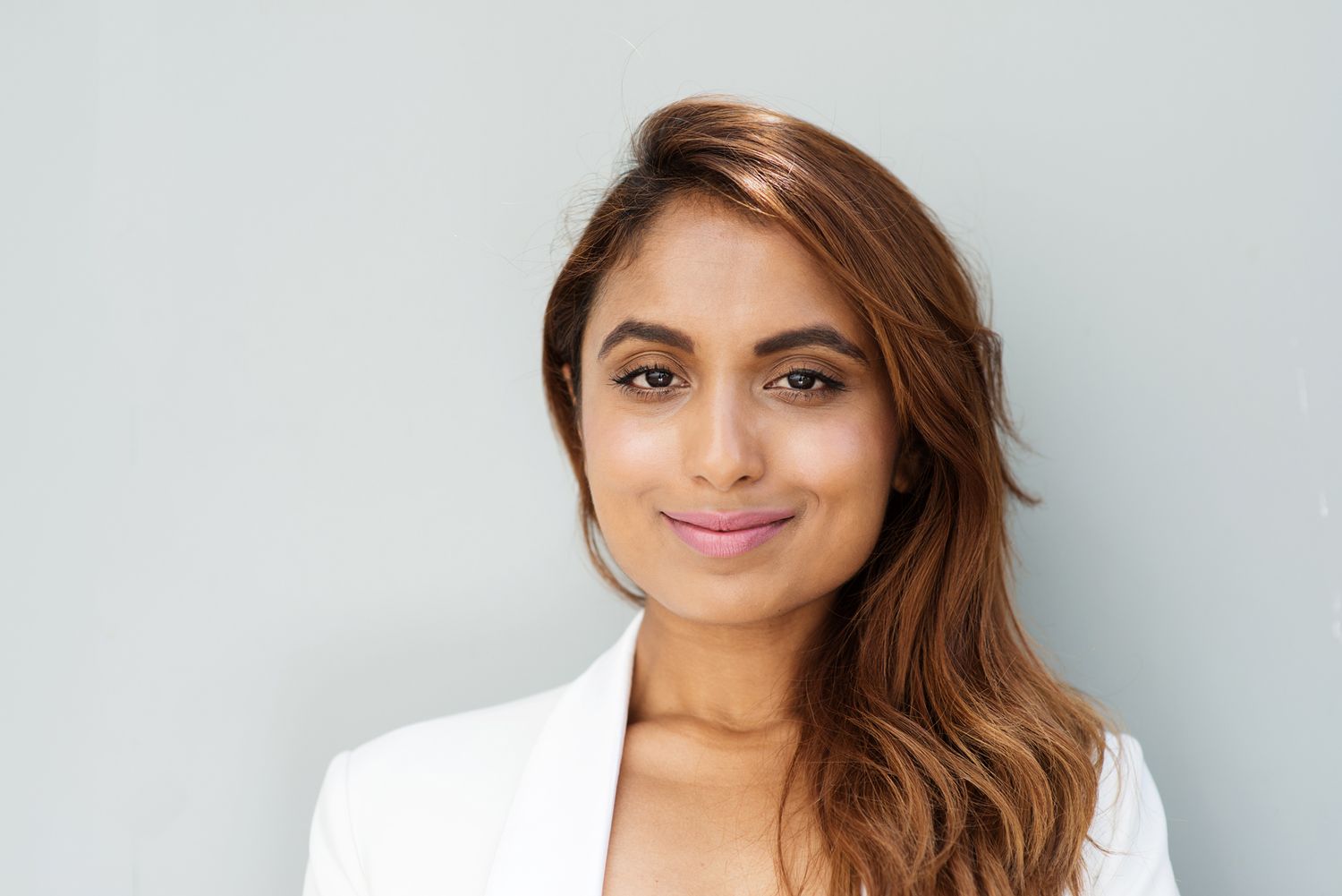 Professional headshots of a woman in a white blazer with flowing hair against a light background.