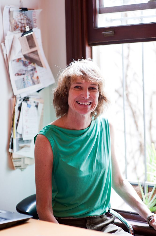 Woman in turquoise sleeveless top sits by window in casual indoor photoshoot series.