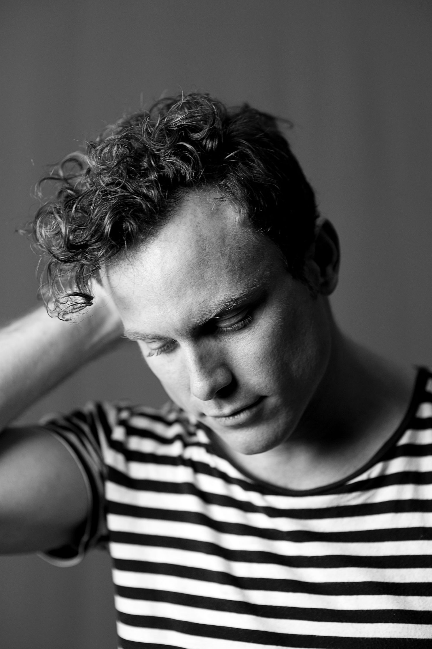 Artistic black and white portraits of someone wearing a striped shirt showing different head positions.