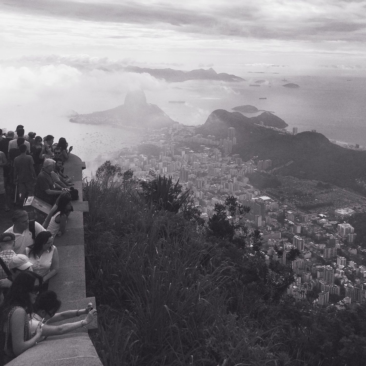 Black and white panoramic view of Rio de Janeiro cityscape with mountains and Sugarloaf Mountain visible in the distance.