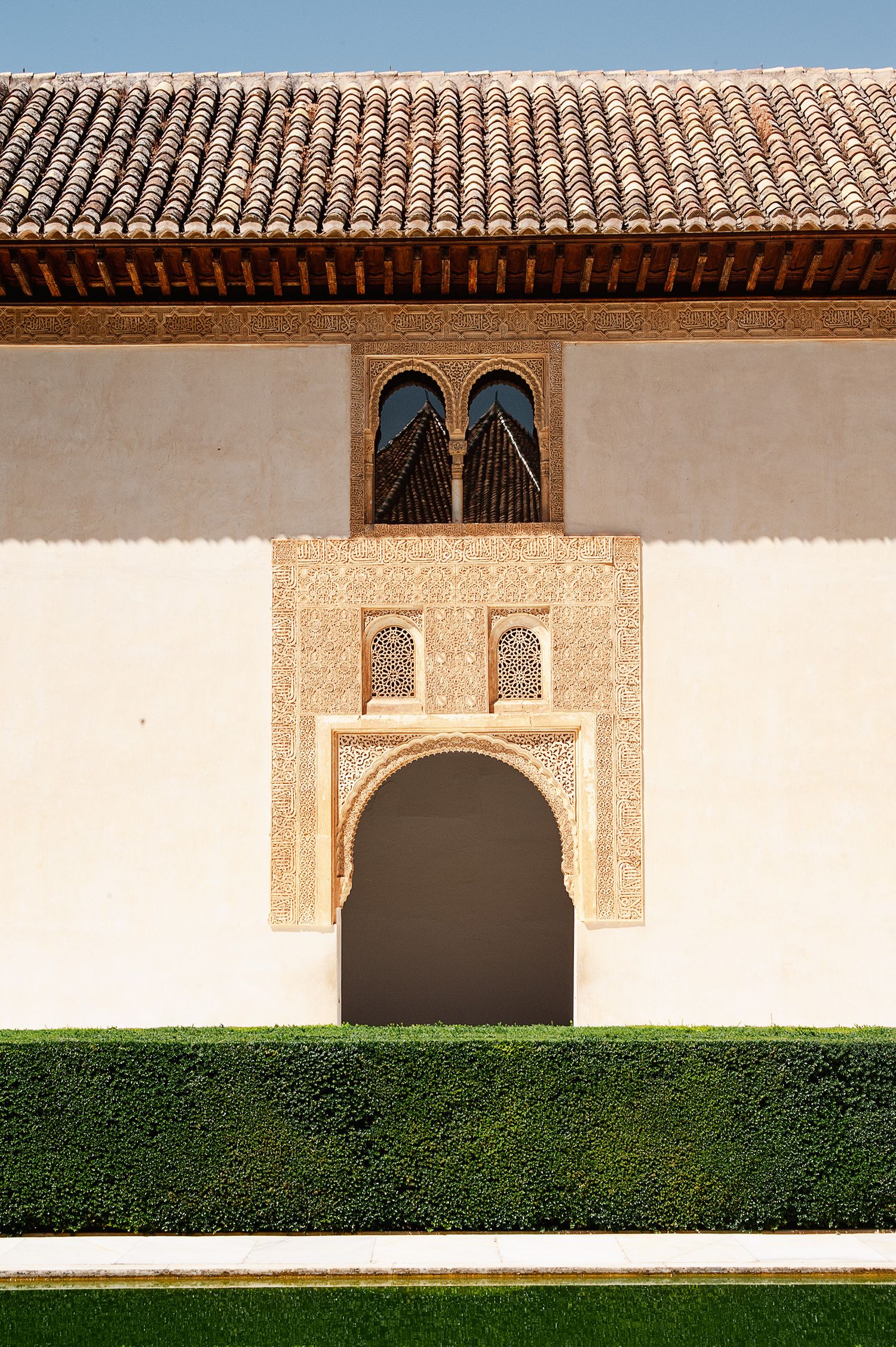 Ornate Moorish architecture at the Alhambra palace features intricate wall carvings and arched doorways with tiled roofs.