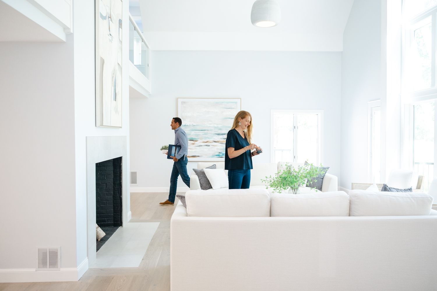 Two people working in modern bright white living room with contemporary furniture.