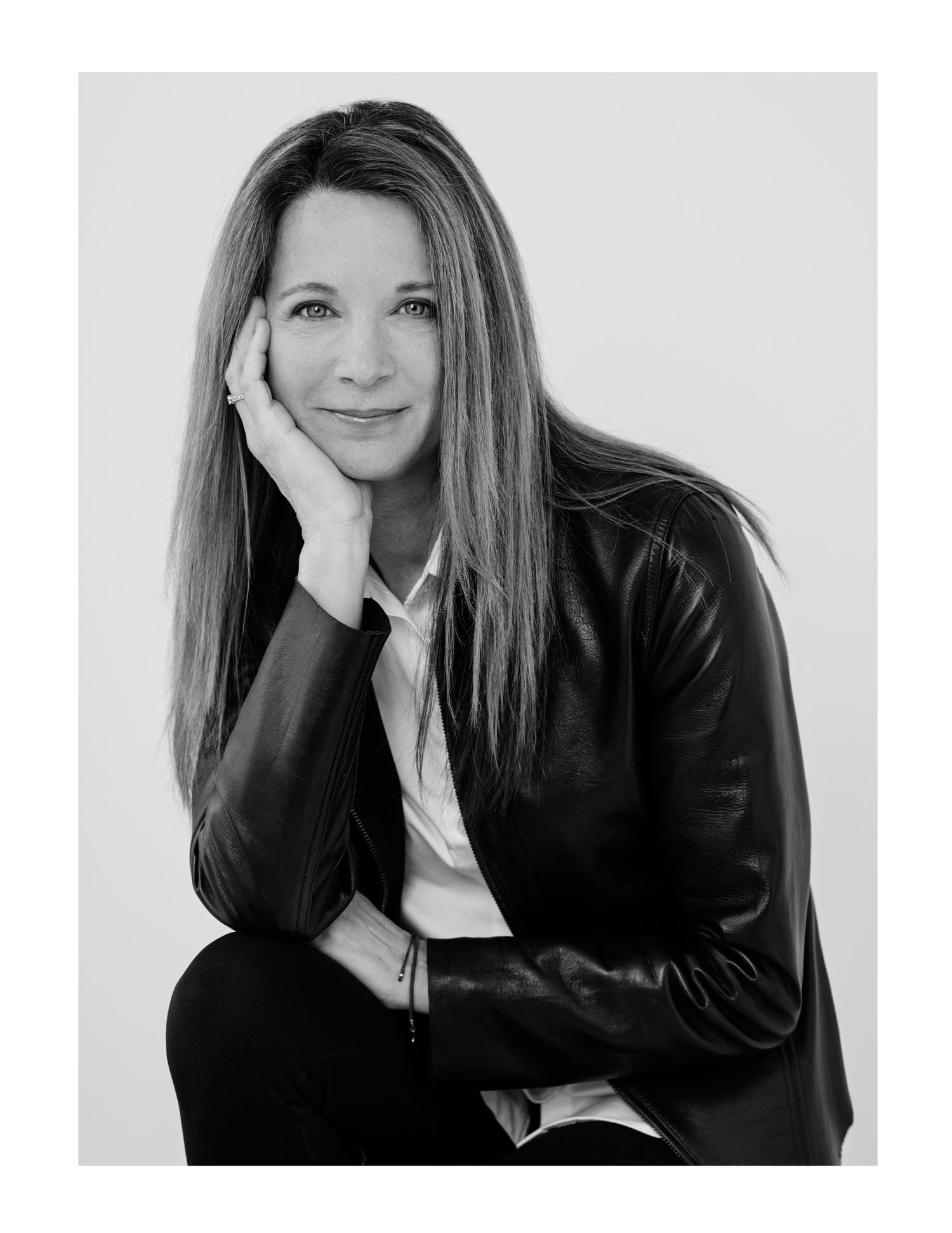 Black and white portrait of a person in leather jacket with hand on face.