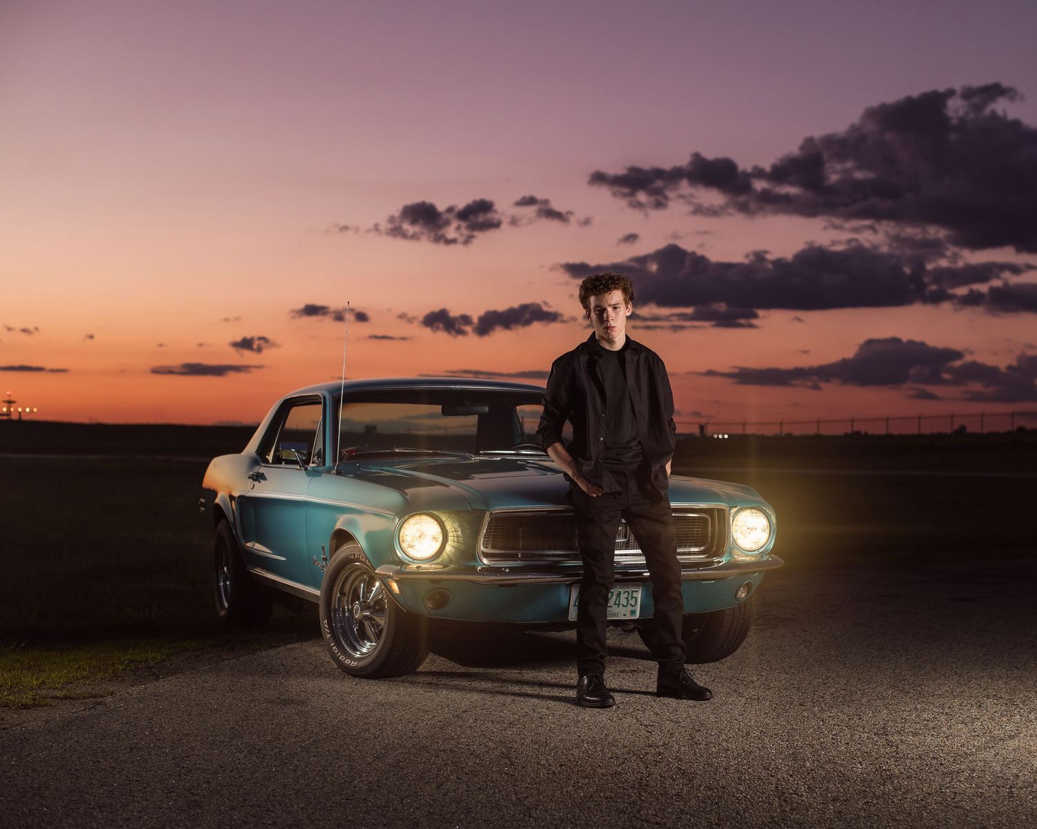 Classic cars illuminated at sunset with dramatic purple sky.