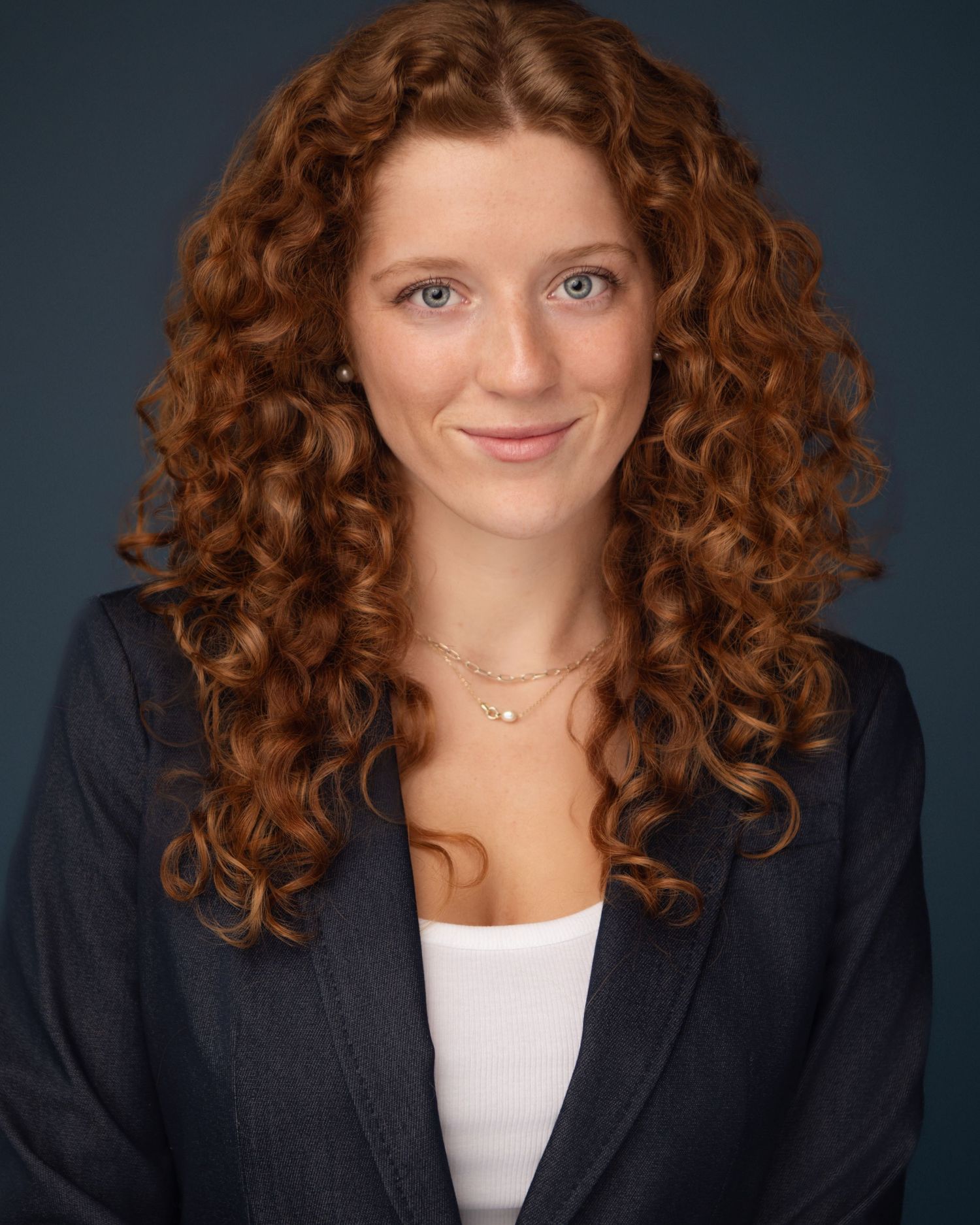 Professional headshots featuring vibrant curly red hair and business attire against a dark background.
