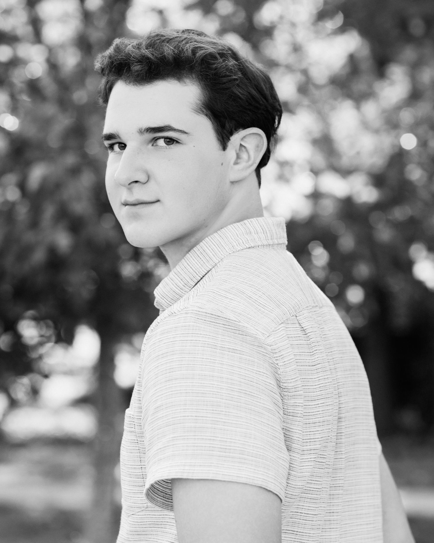 Black and white portrait photo of a young person in a striped polo shirt.