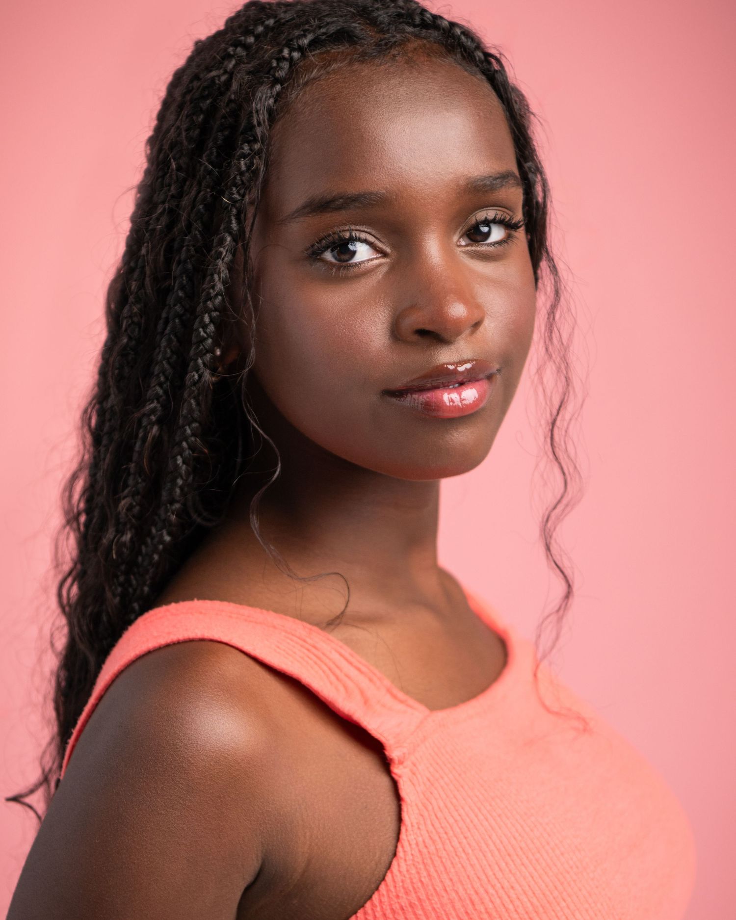 Portrait series against pink background wearing coral top with natural lighting.