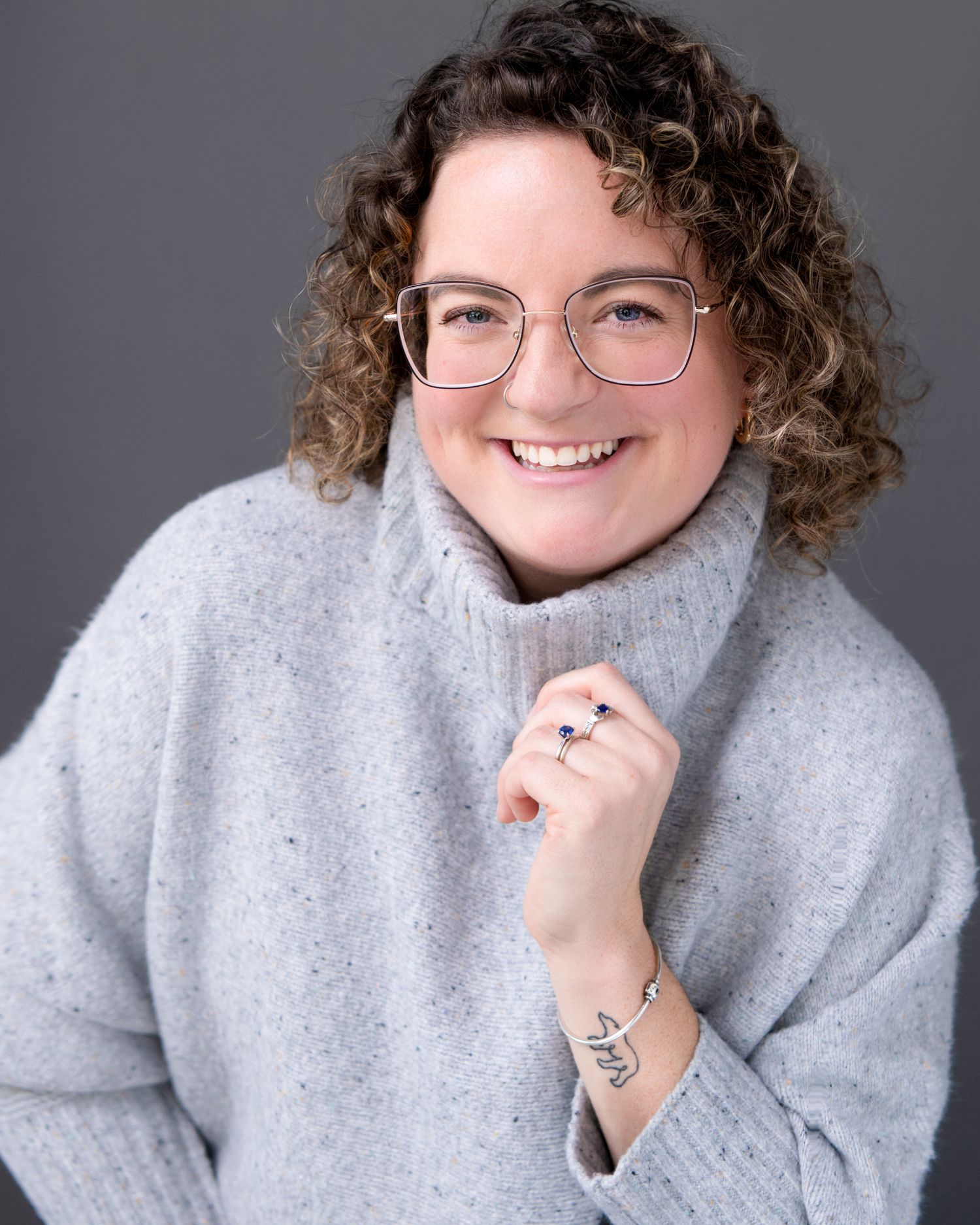 Cozy winter portraits in grey sweater against dark studio background.