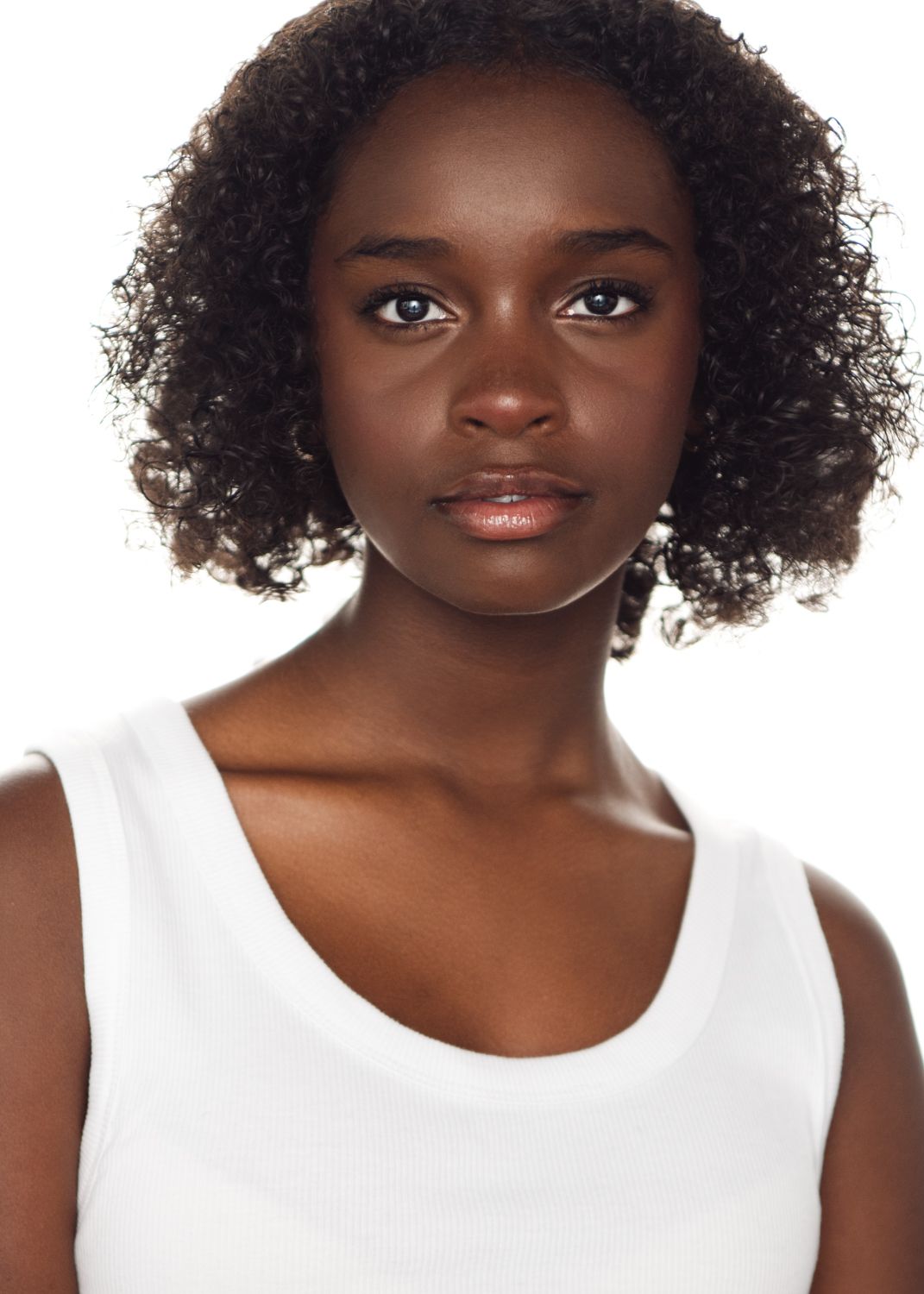 Close-up beauty shots showing natural curly hair and white sleeveless top.