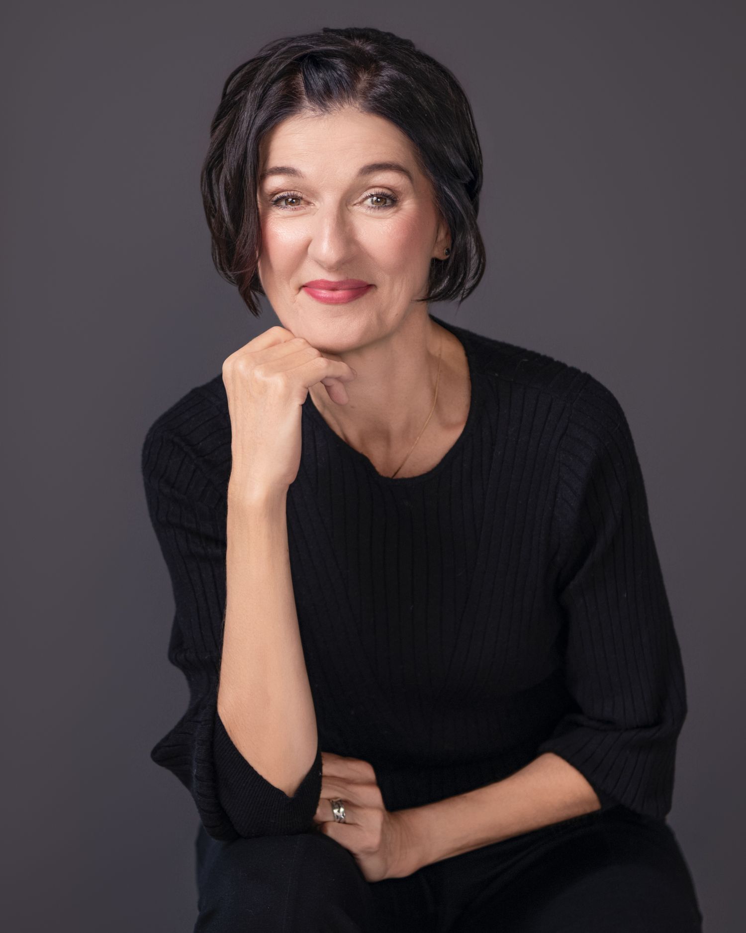 Stylish portraits in black sweater against dark grey studio background.