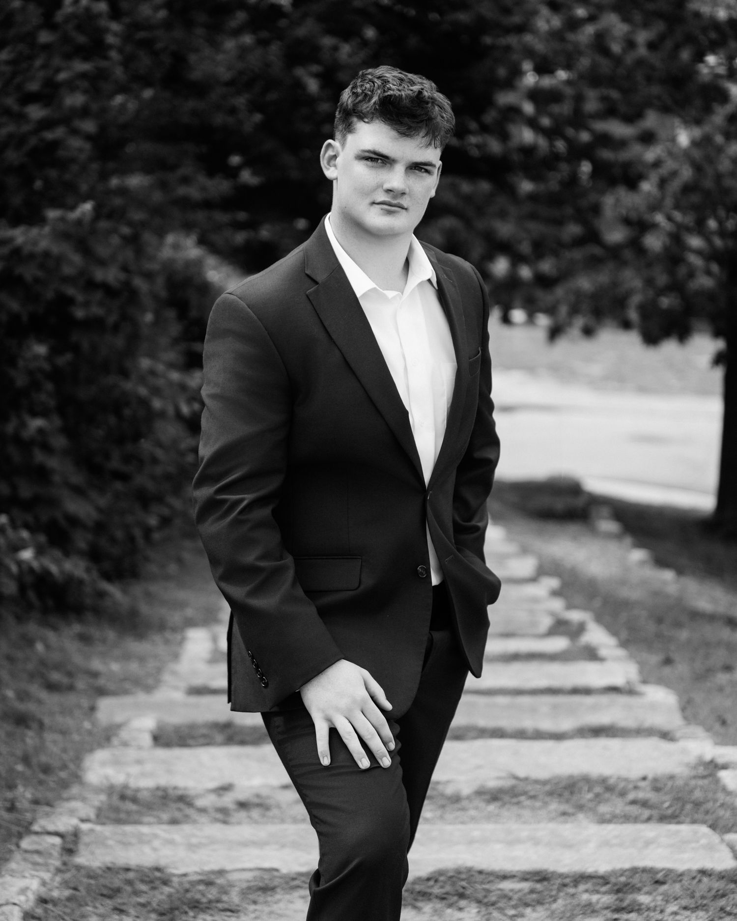 Professional portrait of someone in a dark suit standing on stone steps.