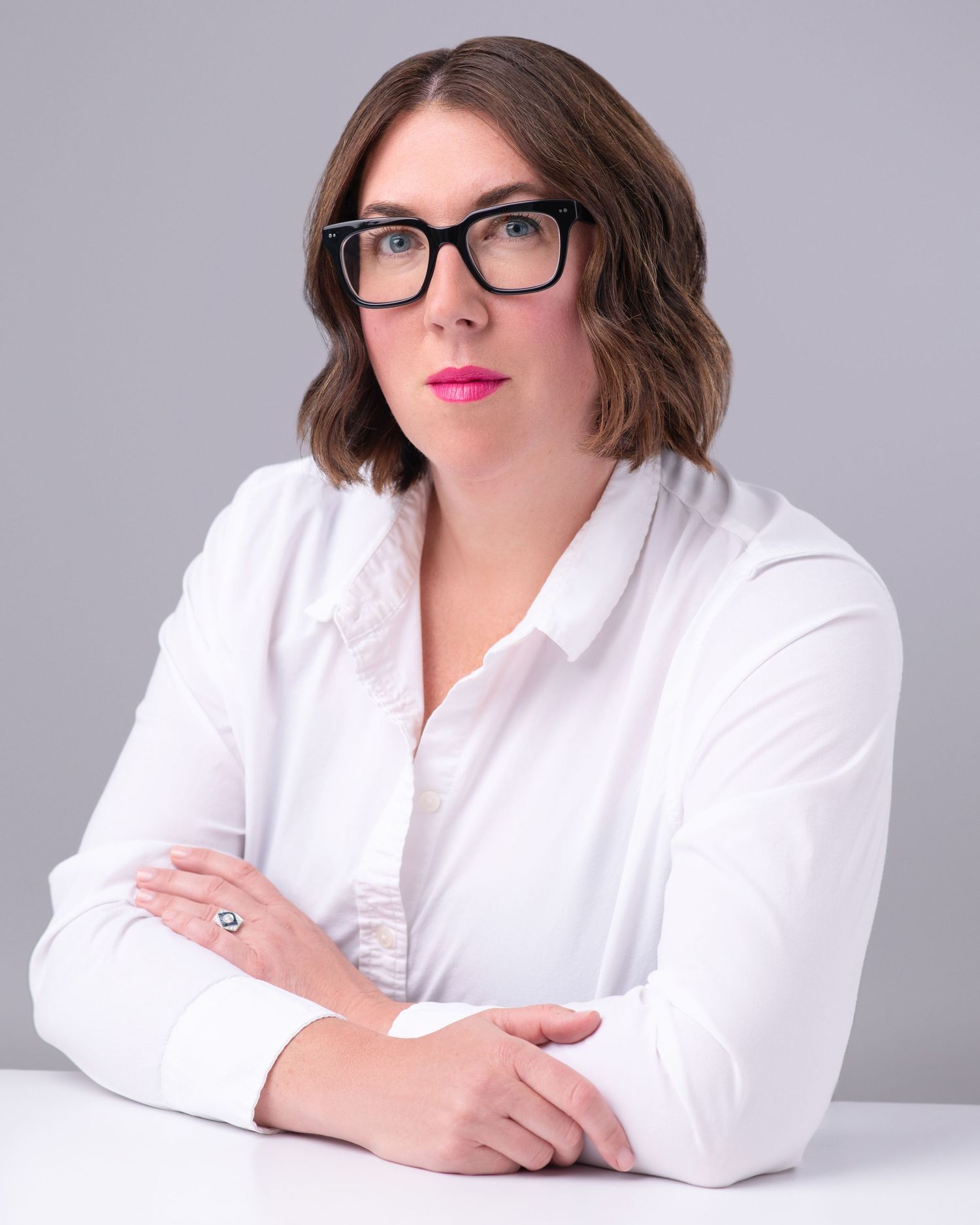 Professional portrait series of someone in a white button-down shirt and glasses against a gray backdrop.