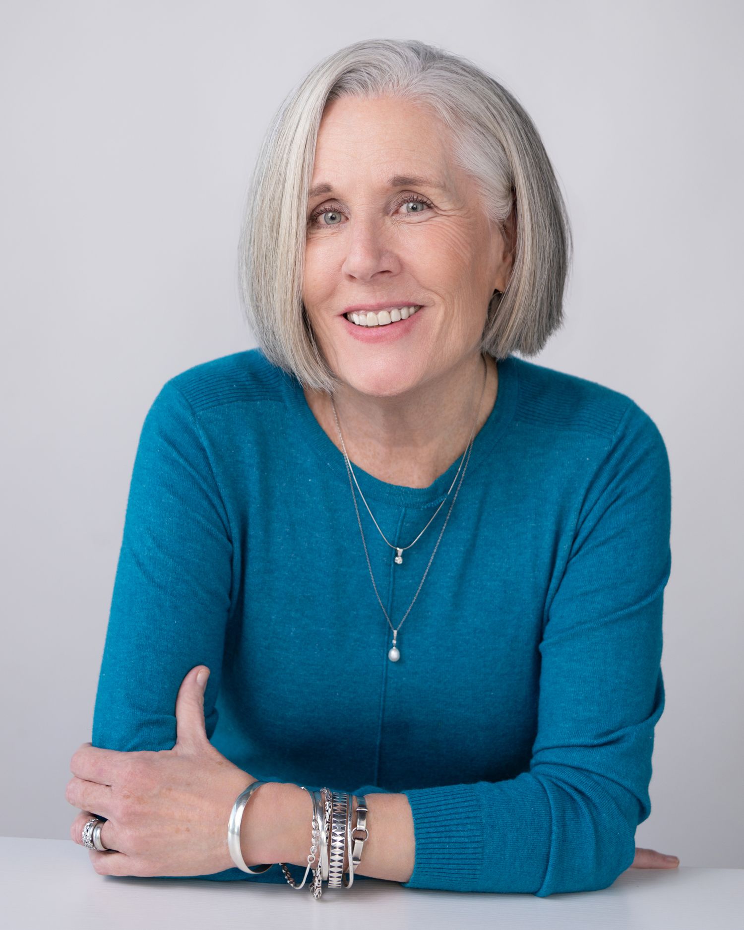 Professional headshot series showing same person in teal sweater against white background from different angles.