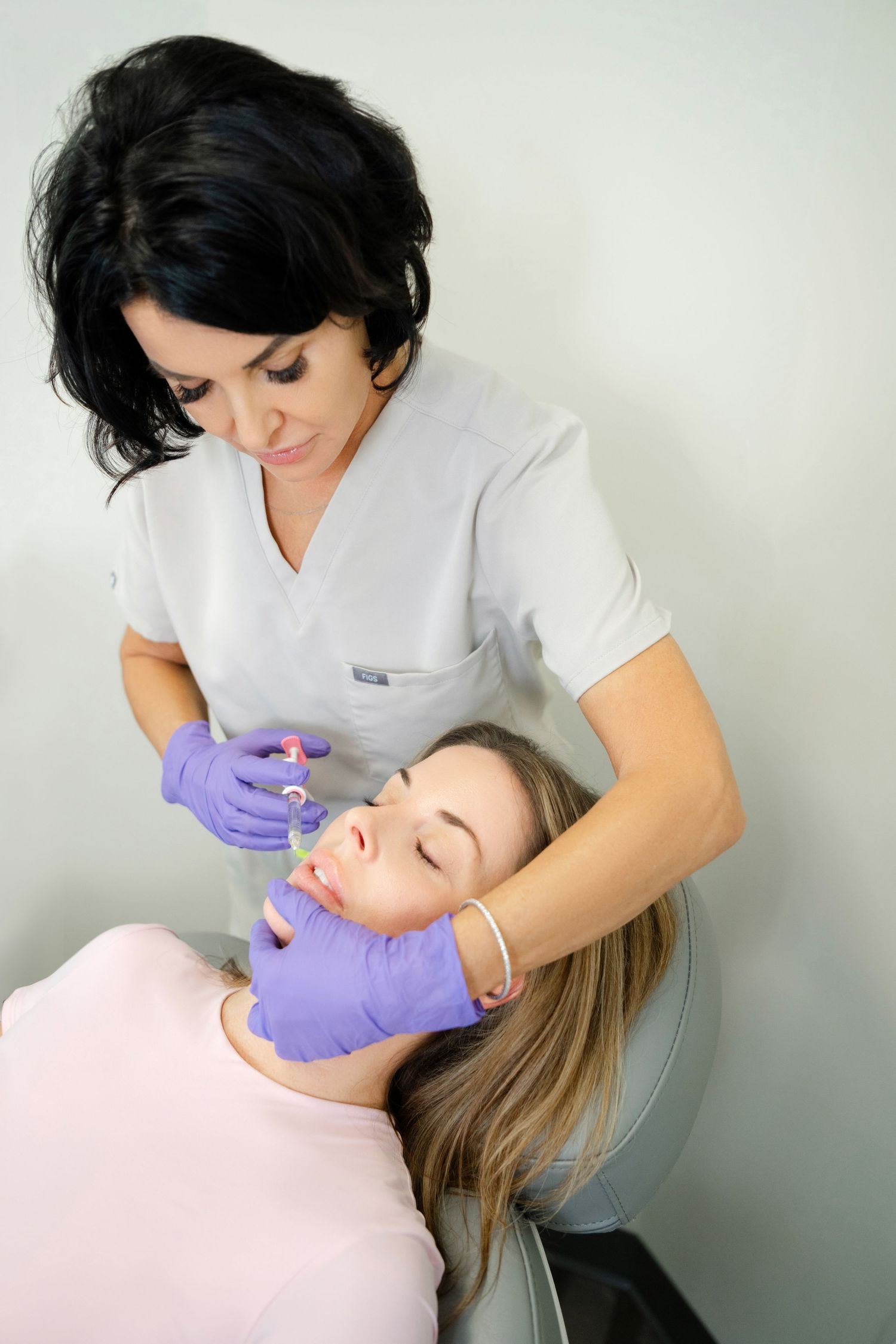 Aesthetic nurse administering facial filler injection to relaxed female patient in medical clinic In North Hampton, NH.