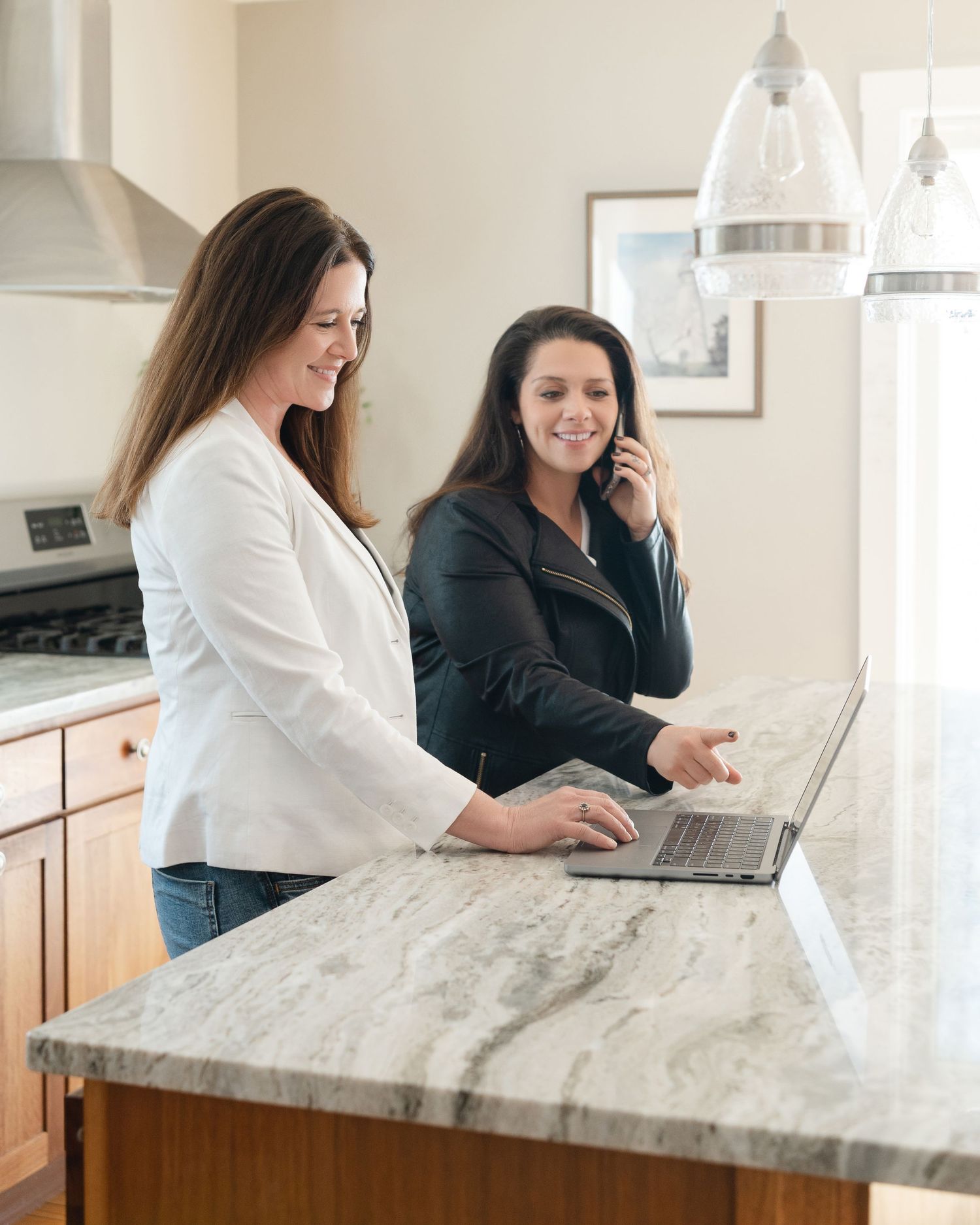 Two professionals working together at marble counter with laptops in modern office setting.
