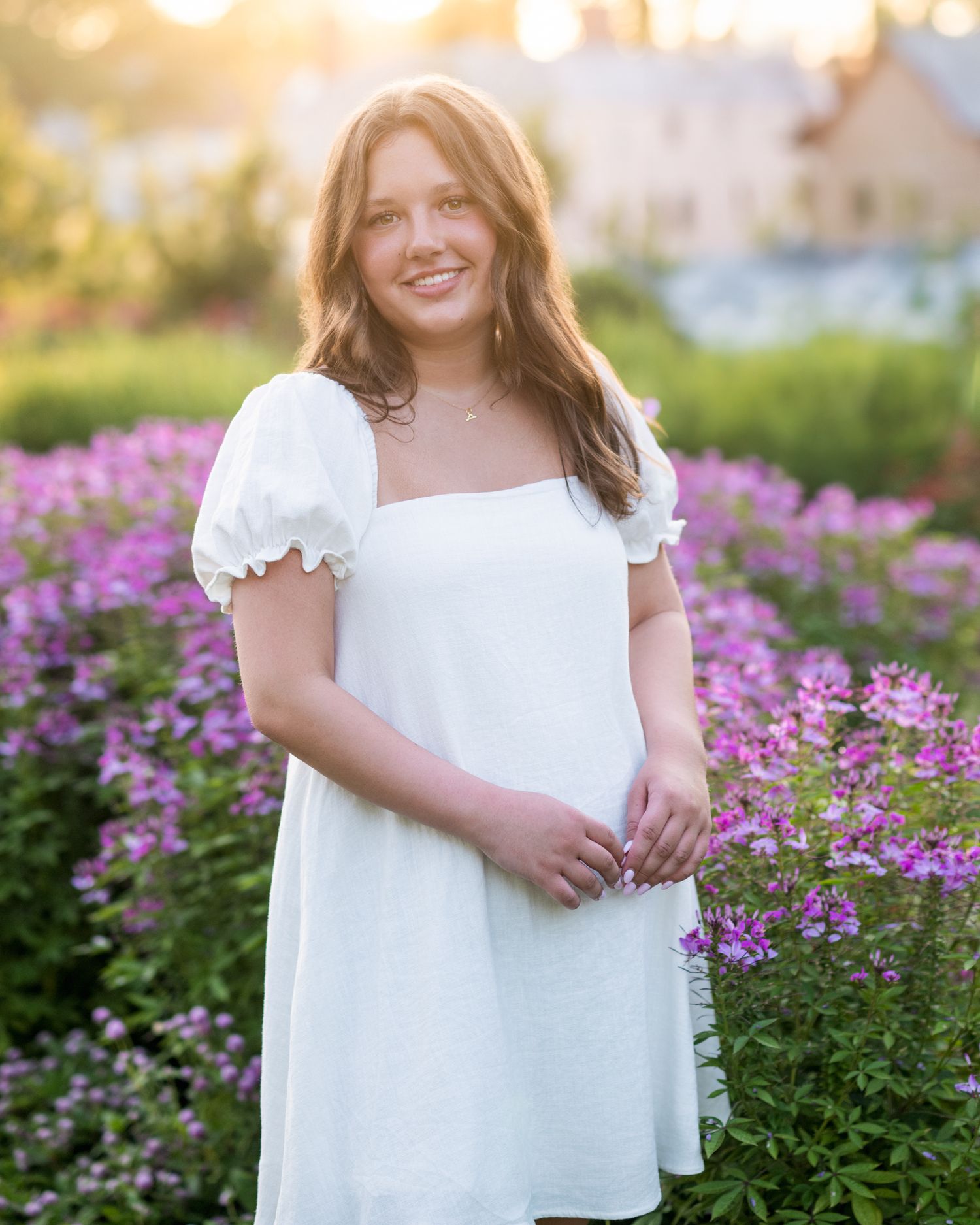 Portrait in white dress among purple wildflowers during golden hour.