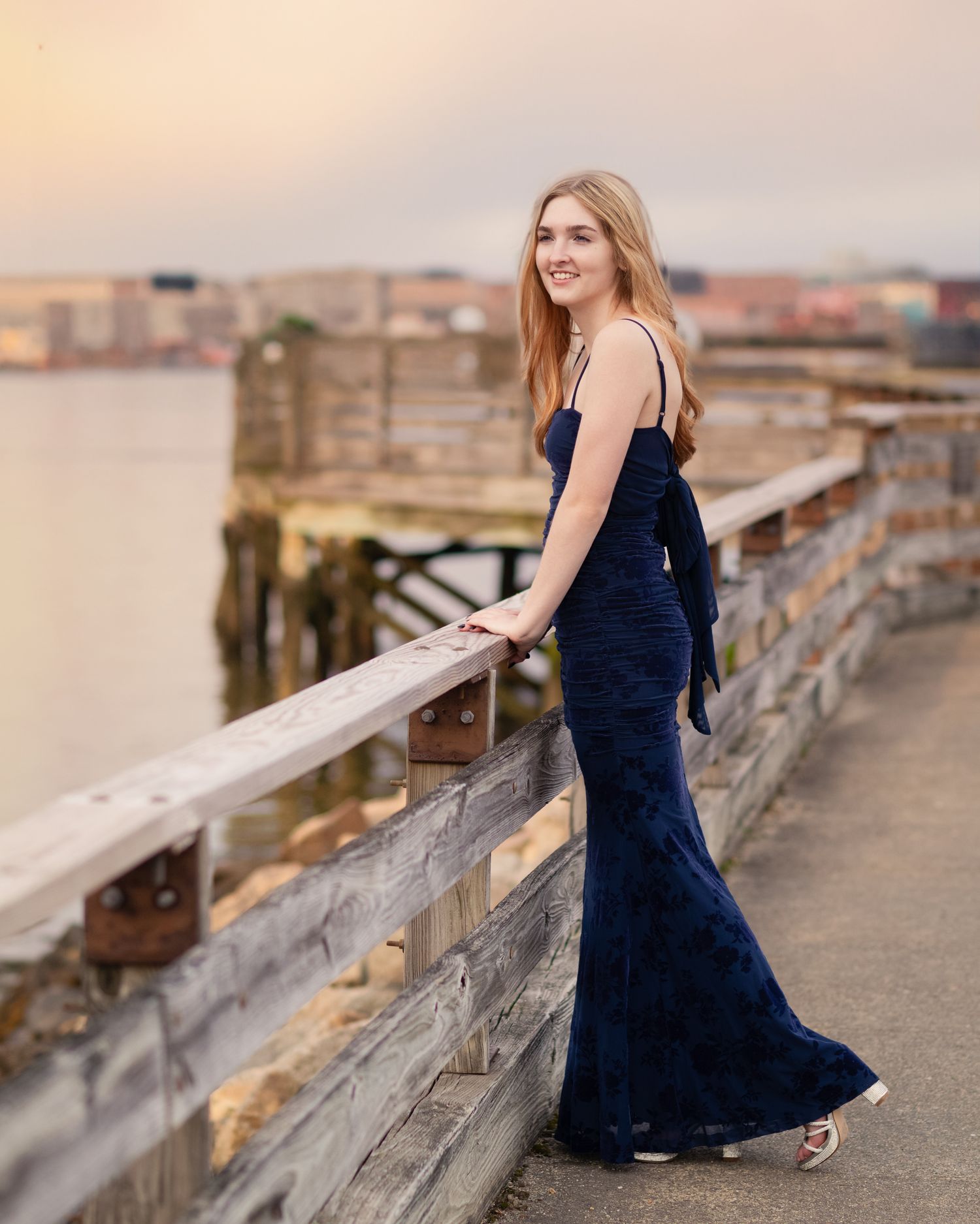 Evening portrait in a navy formal dress on a wooden pier.