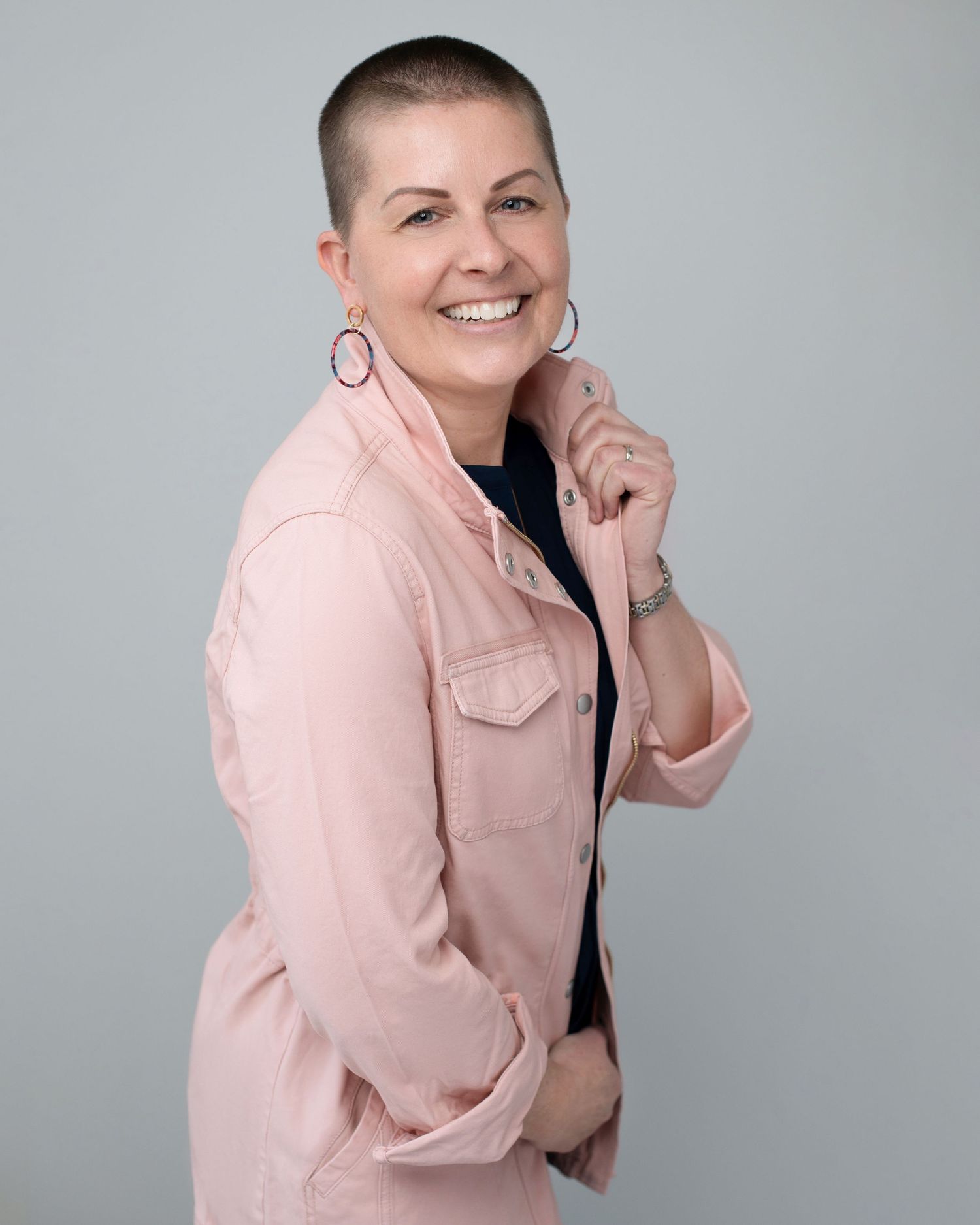 Studio portrait of person in pink denim jacket with short hair.