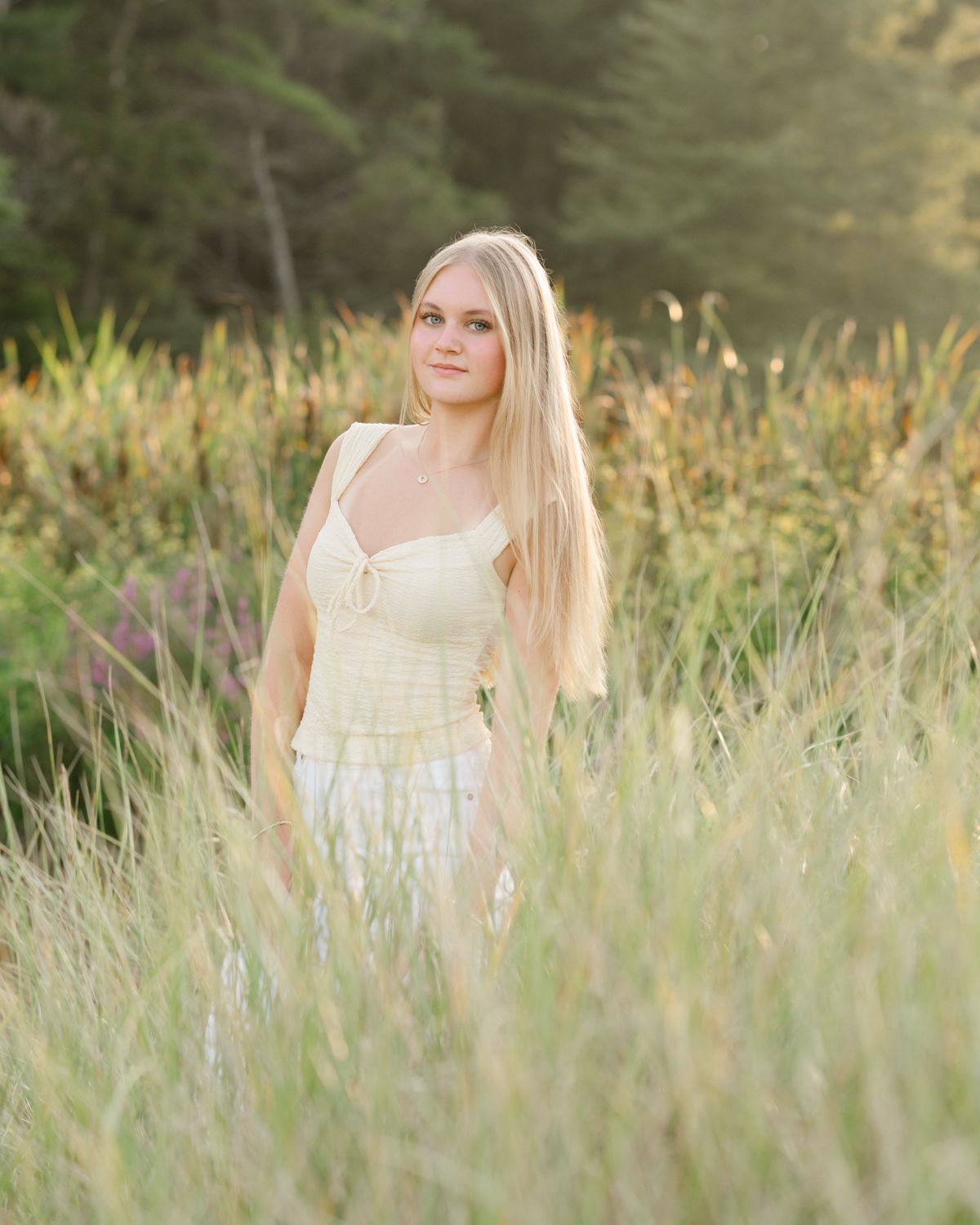 A light summer portrait in a field of tall grass during golden hour.