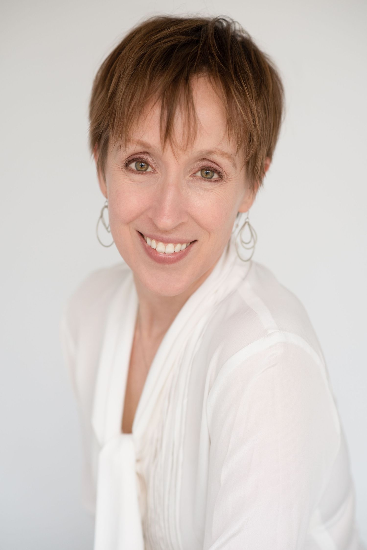 Professional headshot series showing warm expressions against a light background in a white button-up top.