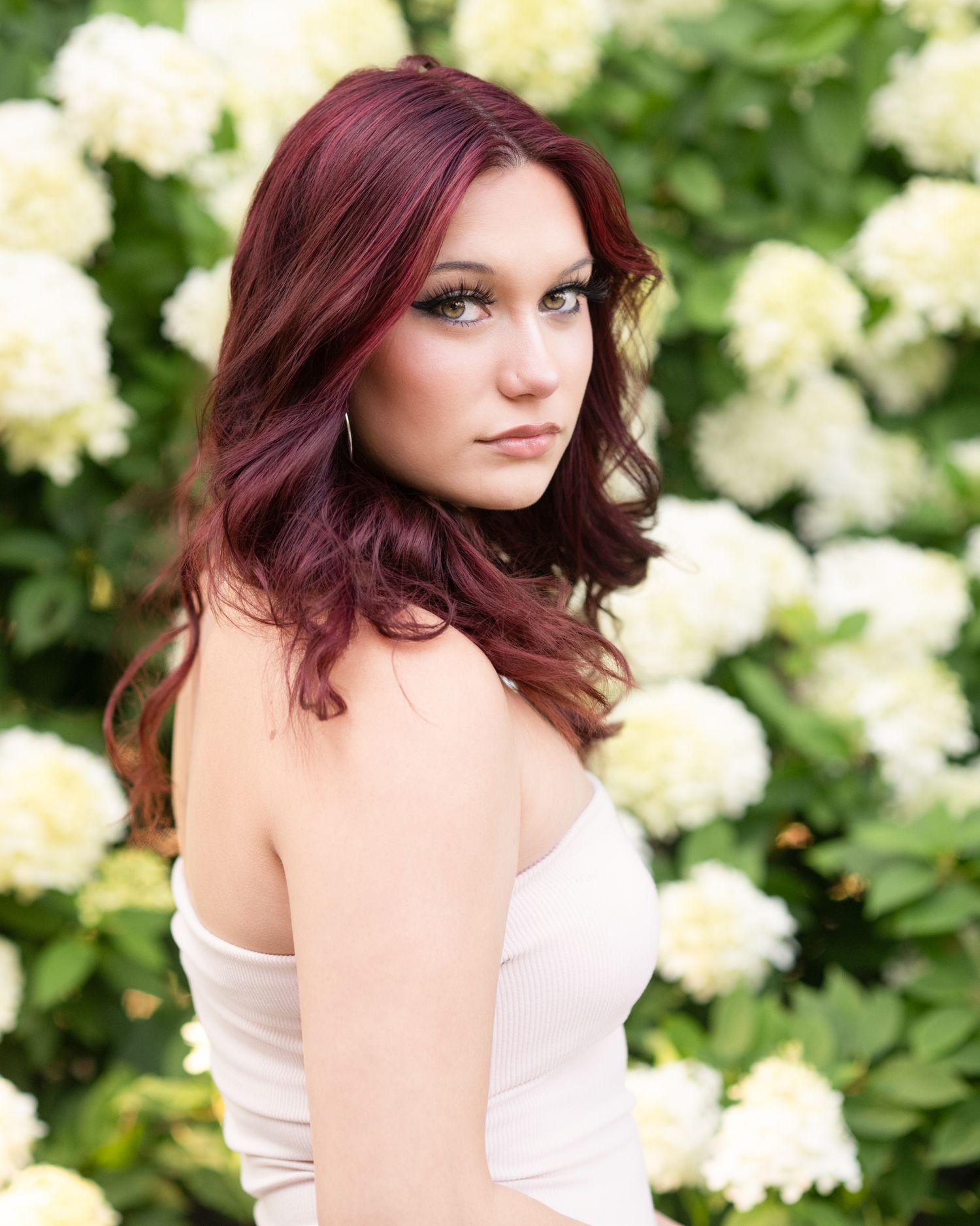 Outdoor portrait series with white hydrangea flowers creating a natural garden backdrop.