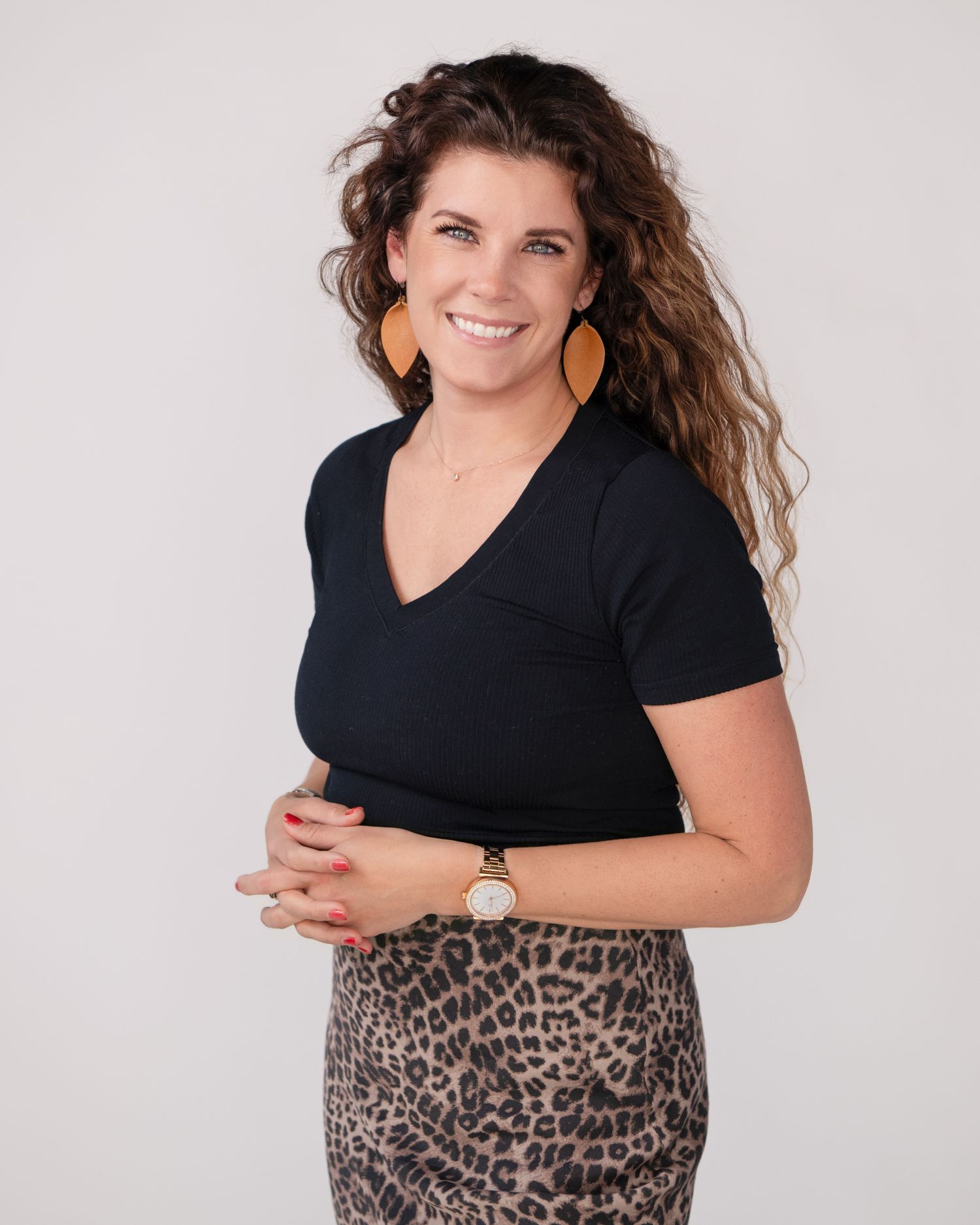 Professional portrait against white background wearing black top and leopard print skirt.
