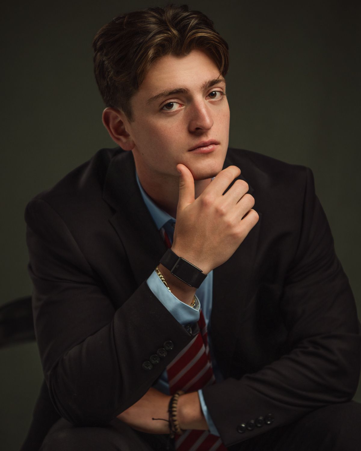 Dramatic portrait of a person in business attire against dark green background.