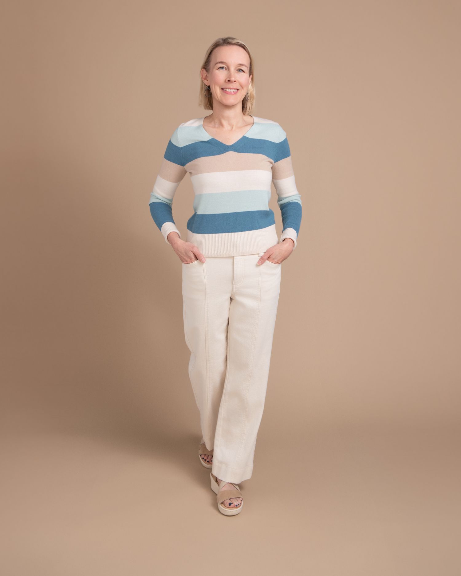 Fashion series showing casual outfit with blue and white striped top and cream pants.