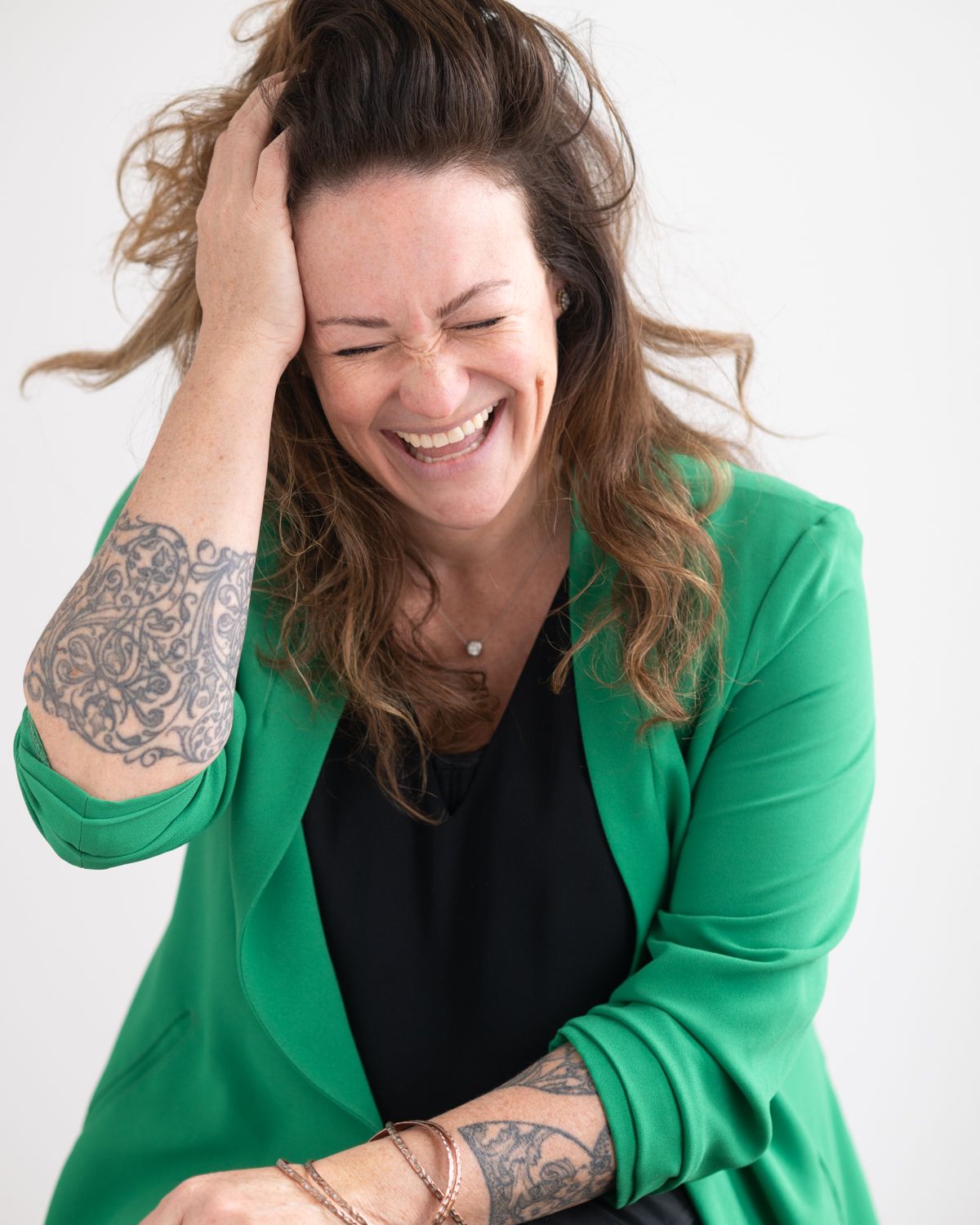 Professional portrait series showing joyful expressions while wearing a green blazer against white background.