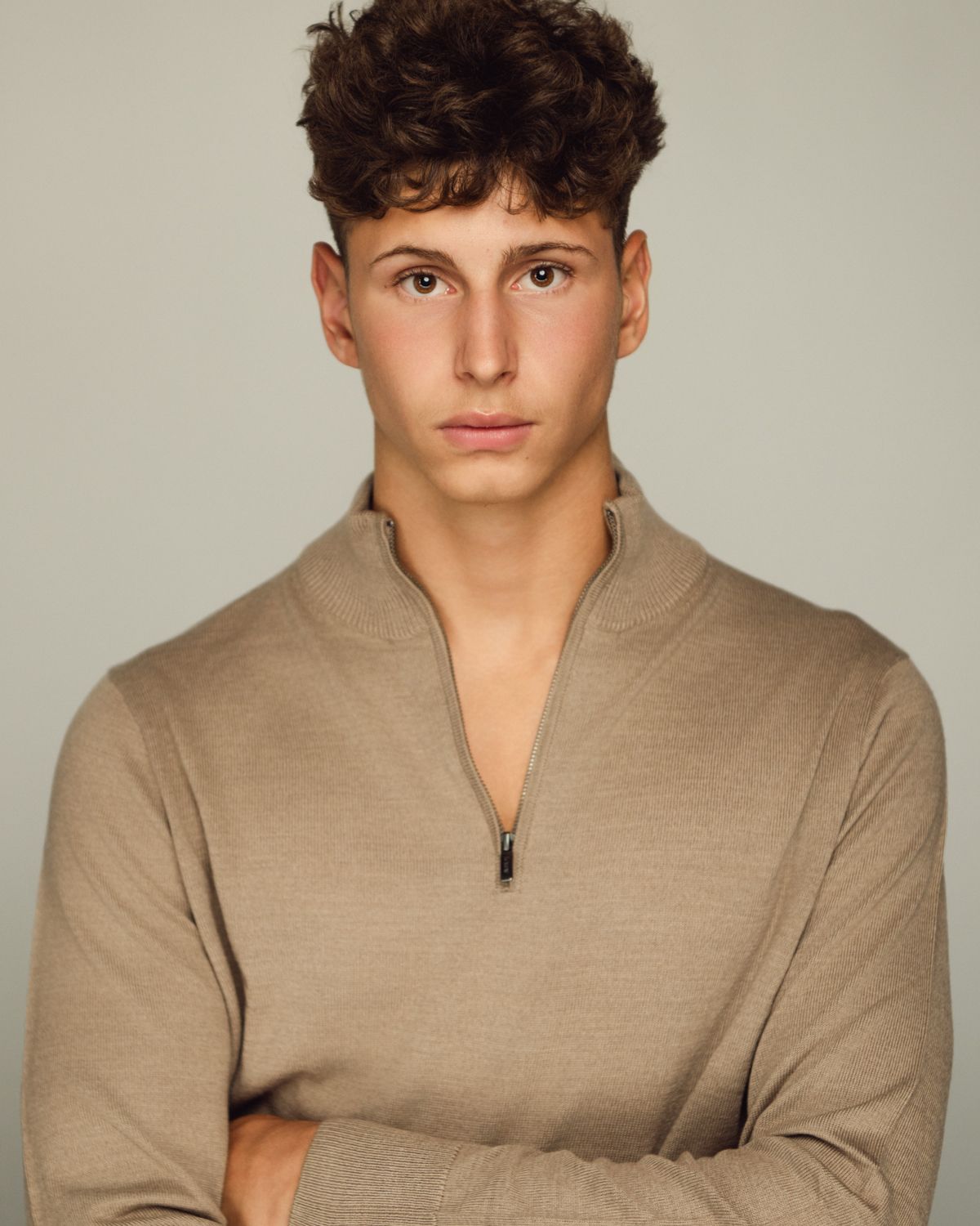 Portrait series in a beige quarter-zip sweater against neutral background.