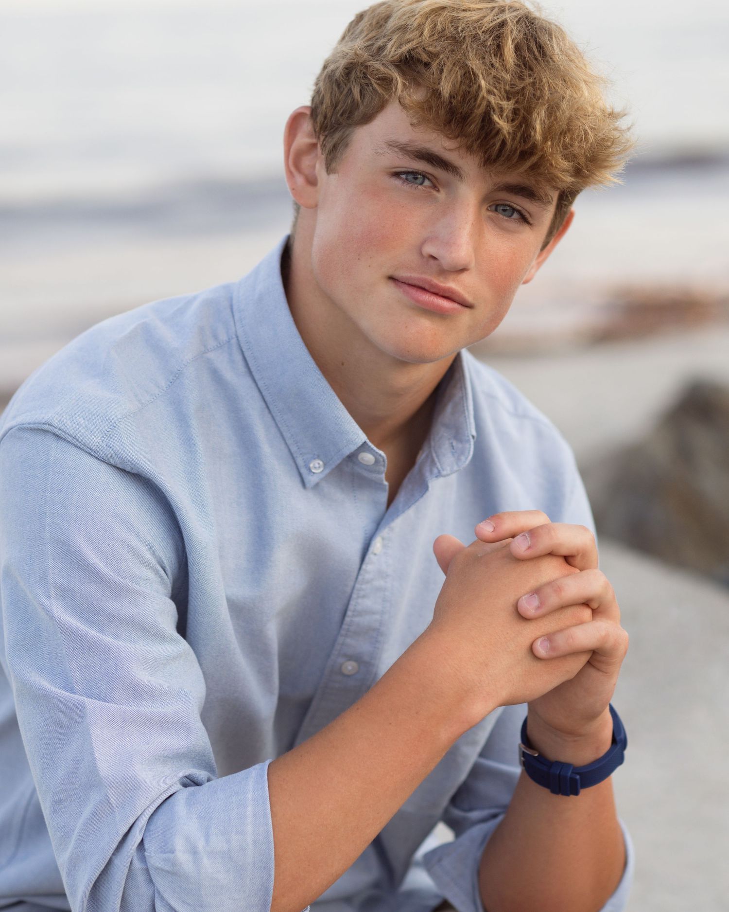 Young person in light blue button-down shirt posing for casual outdoor portraits.