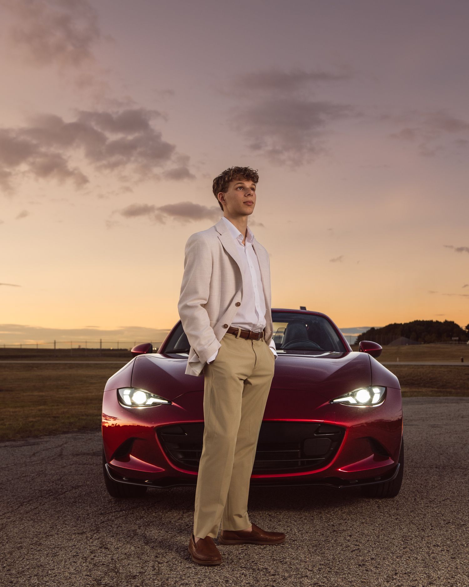 Stylish portrait with a red sports car during sunset.